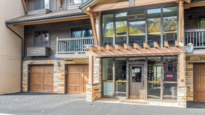 A two-story building with a stone facade, large windows, and a wooden balcony. - Cozy 2-Bedroom Ground-Floor Condo at The Phoenix – Steps from the Slopes! (Steamboat Springs)