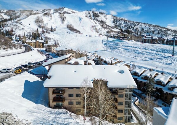 A snow-covered mountain resort with a ski lift, buildings, and a parking area. - Slopeside Ski Getaway | Fireside + Hot Tub (Steamboat Springs)
