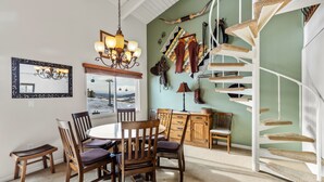 Un coin repas avec une table ronde, des chaises en bois et un lustre.