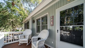 Eine Veranda mit zwei Schaukelstühlen, einem weißen Geländer und einem großen Fenster.