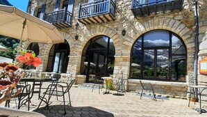 A stone building with arched windows and outdoor seating. - Hôtel Vignemale (Gavarnie-Gedre)