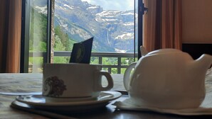 A hotel room with a bed, a cup and saucer, and a view of mountains through a window. - Hôtel Vignemale (Gavarnie-Gedre)