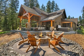 Un chalet doté d’un foyer extérieur, de sièges de jardin et d’une cheminée en pierre.