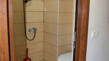 A bathroom with a shower, toilet, and a broom.