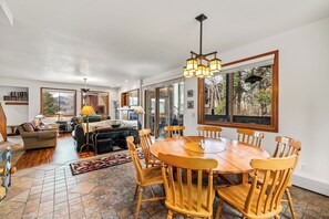 A spacious living room with a wooden dining table and chairs, a sofa, and a coffee table.