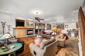 Cozy living area with a central fireplace, two sofas, and a dining table.