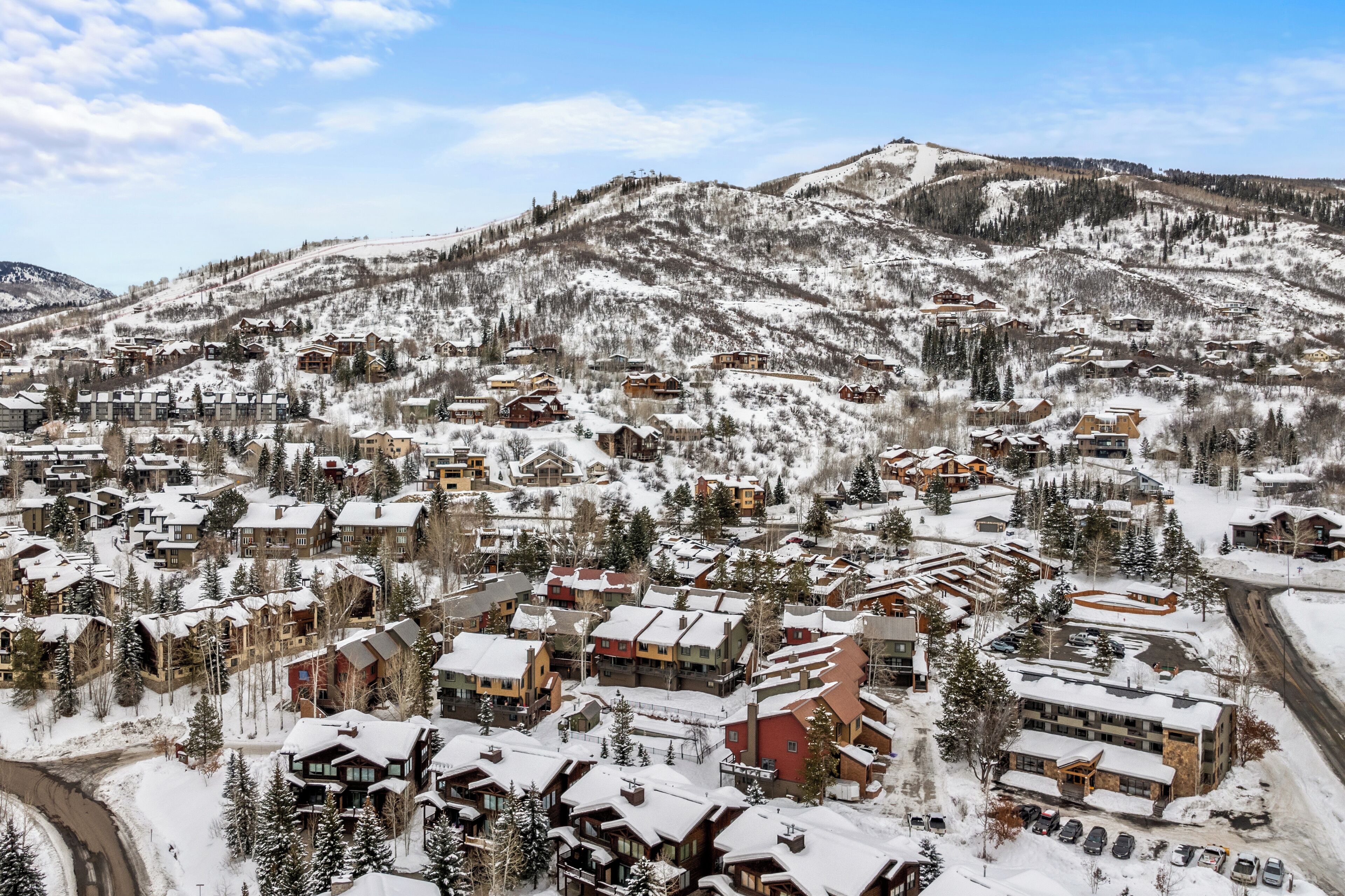 Un paese montano innevato con diversi edifici, tra cui hotel e chalet, e una seggiovia sullo sfondo.