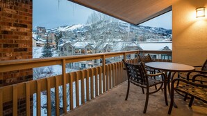 Un balcon donnant sur une montagne enneigée et des bâtiments.