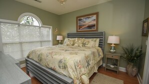 A bedroom with a bed, bedside tables, a lamp, and a window with blinds. - 4673 Wild Iris Dr 203 2 Bedroom Condo by Redawning (Myrtle Beach)