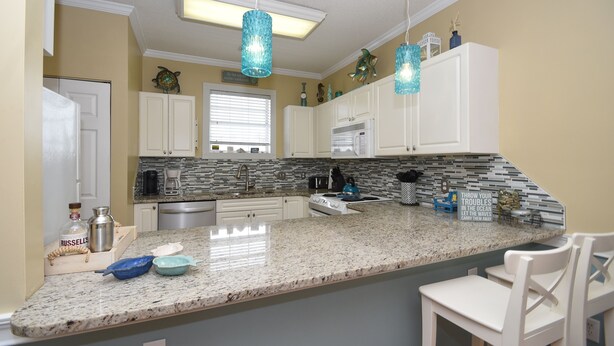 A kitchen with white cabinets, a granite countertop, and pendant lights. - 4673 Wild Iris Dr 203 2 Bedroom Condo by Redawning (Myrtle Beach)