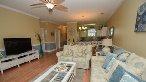 A living room with a television, sofa, and coffee table. - 4673 Wild Iris Dr 203 2 Bedroom Condo by Redawning (Myrtle Beach)