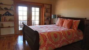 A bedroom with a bed, wooden floor, a bookshelf, a desk, and a window. - Flying Monkey Mesa | Near Zion | Rustic Mtn Home (Virgin)