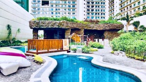 Una piscina con cubierta de madera y jardín de rocas.