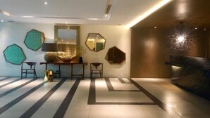 Ein modernes Interieur mit geometrischem Bodenmuster, einem zentralen Tisch mit Stühlen und dekorativen Spiegeln an den Wänden.