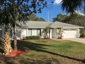 A single-story house with a garage, surrounded by a well-maintained lawn and small trees. - 7BR Pool Home Emerald Island by SHV-8409 (Kissimmee)