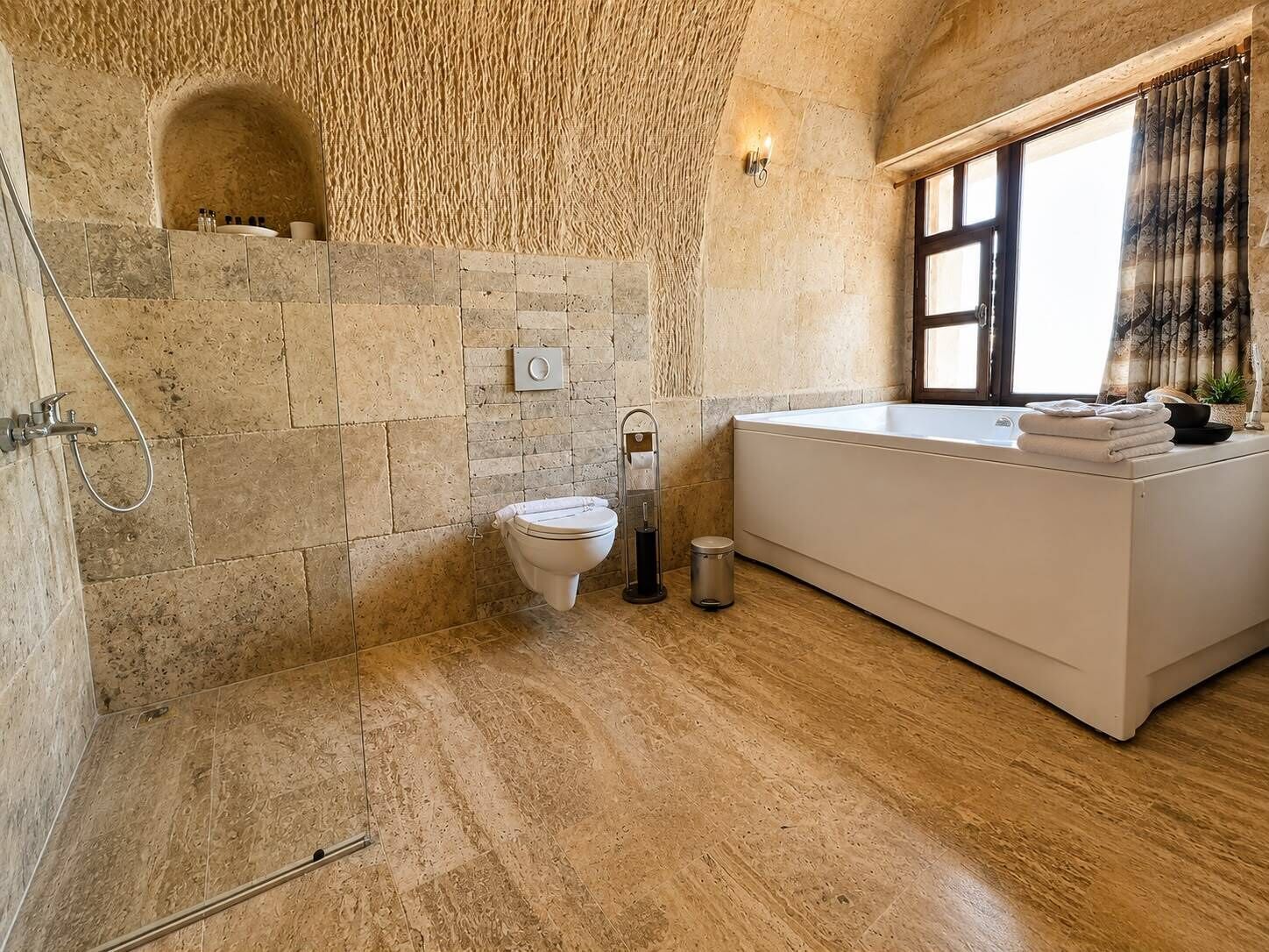 Un baño con pared de piedra, una bañera, un inodoro y una ducha.