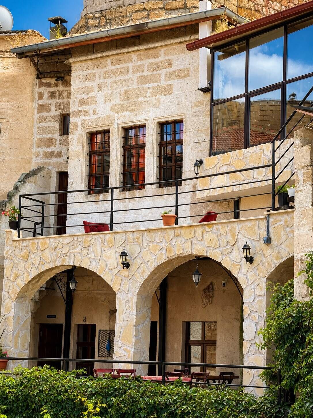 A stone building with a balcony, arched windows, and outdoor seating.