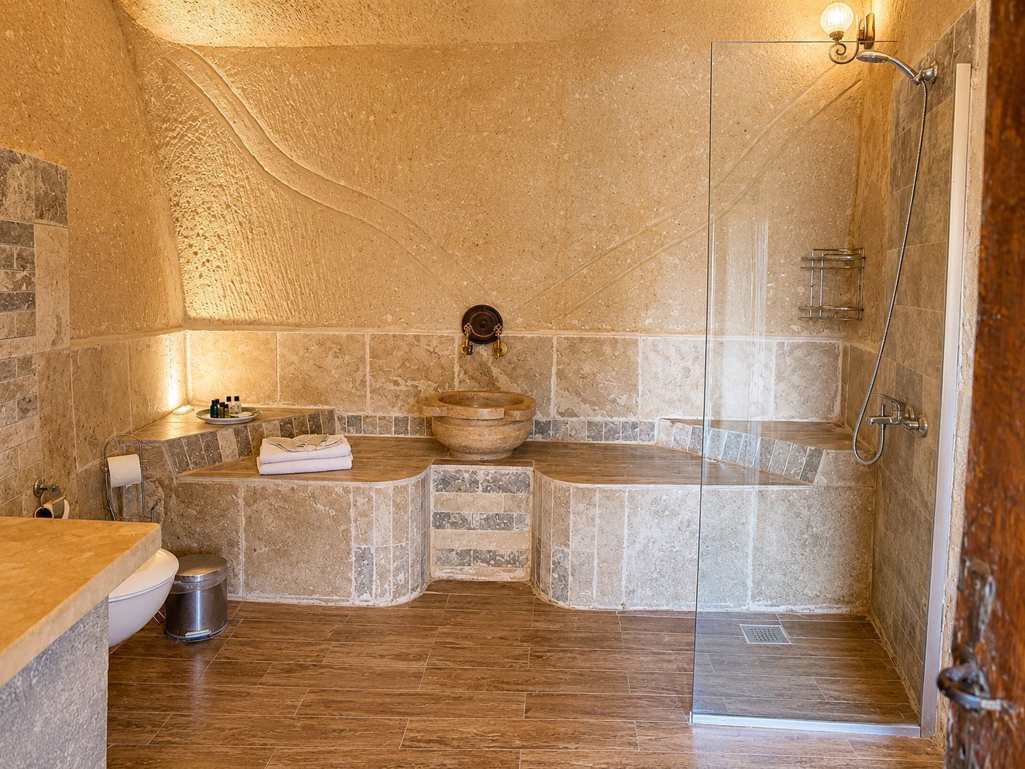 A bathroom with a stone sink, a bathtub, a shower, and a toilet.