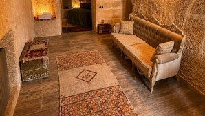 A cozy interior with a sofa, rugs, and a fireplace. - Cappadocia Cave House (Ürgüp)