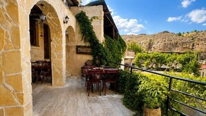 A stone building with outdoor seating and a view of the countryside. - Cappadocia Cave House (Ürgüp)