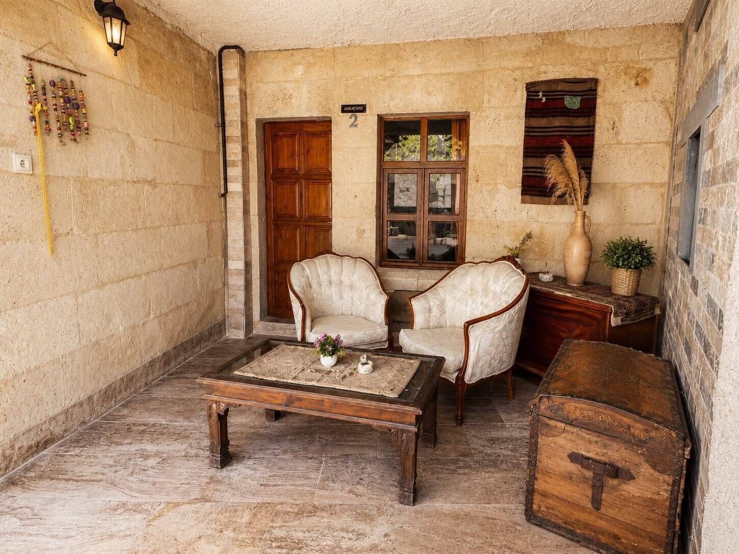 A cozy room with two upholstered chairs, a wooden coffee table, a wooden chest, and a window with a view.