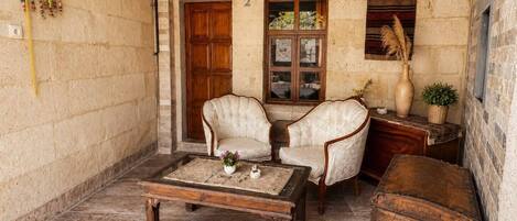 A cozy room with two upholstered chairs, a wooden coffee table, a wooden chest, and a window with a view.