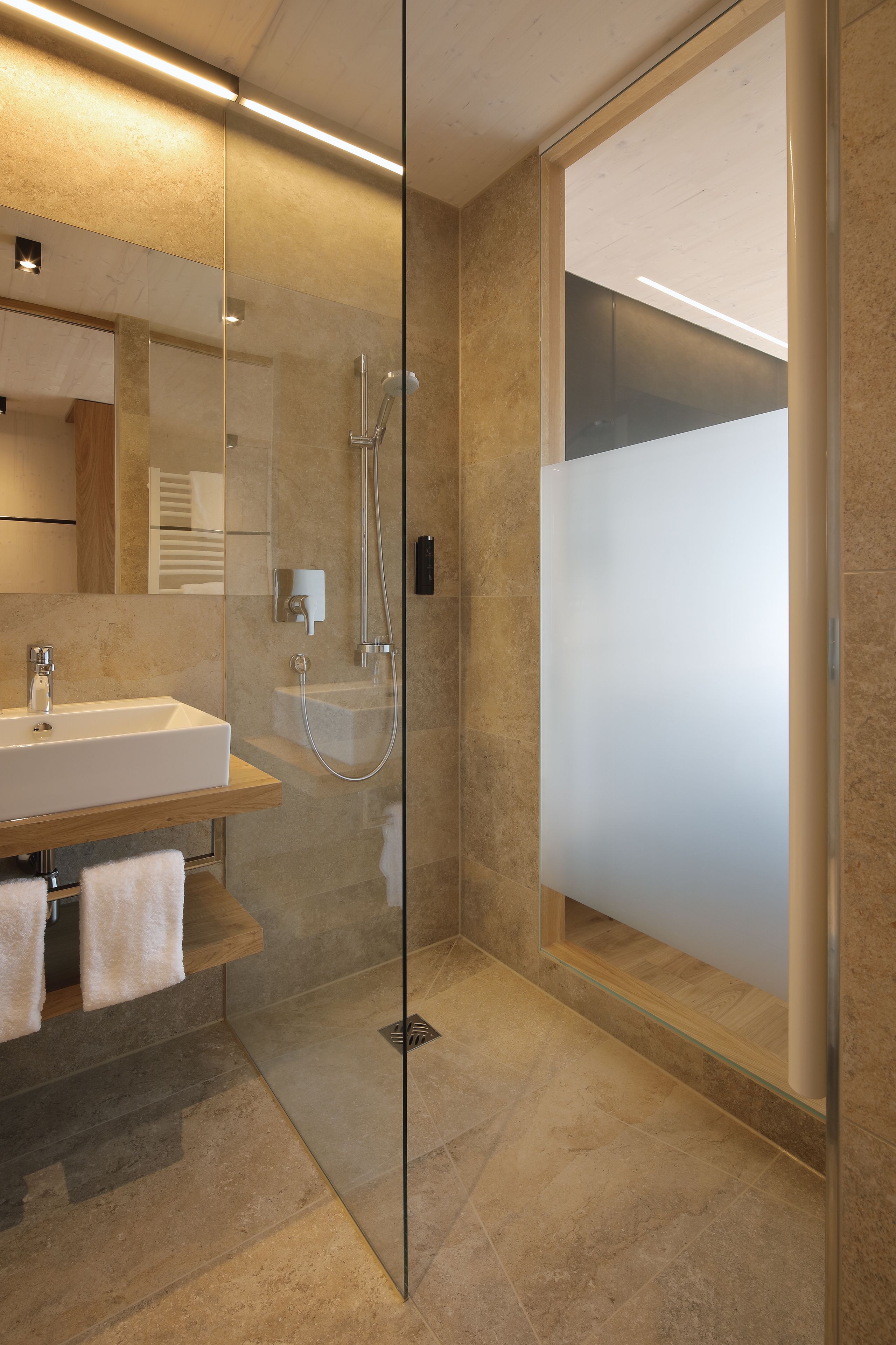 A modern bathroom with a glass-enclosed shower, a sink, and a mirror.