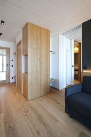 A modern interior with wooden flooring, a grey sofa, and a built-in wardrobe. - 2nd Home Hotel (Nördlingen)