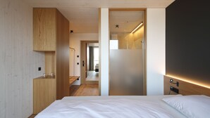 Un dormitorio moderno con una cama grande, un armario de madera y vistas a otra habitación.