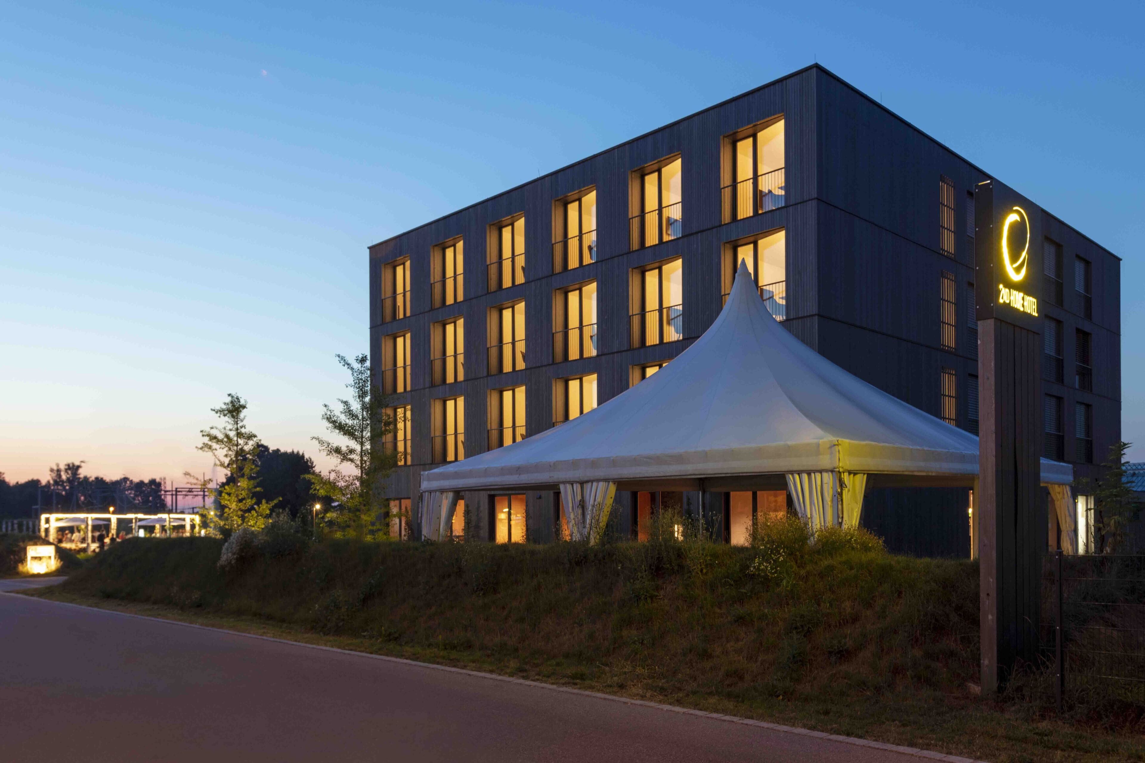 Un hôtel moderne, avec une grande structure en forme de tente blanche à l’avant.