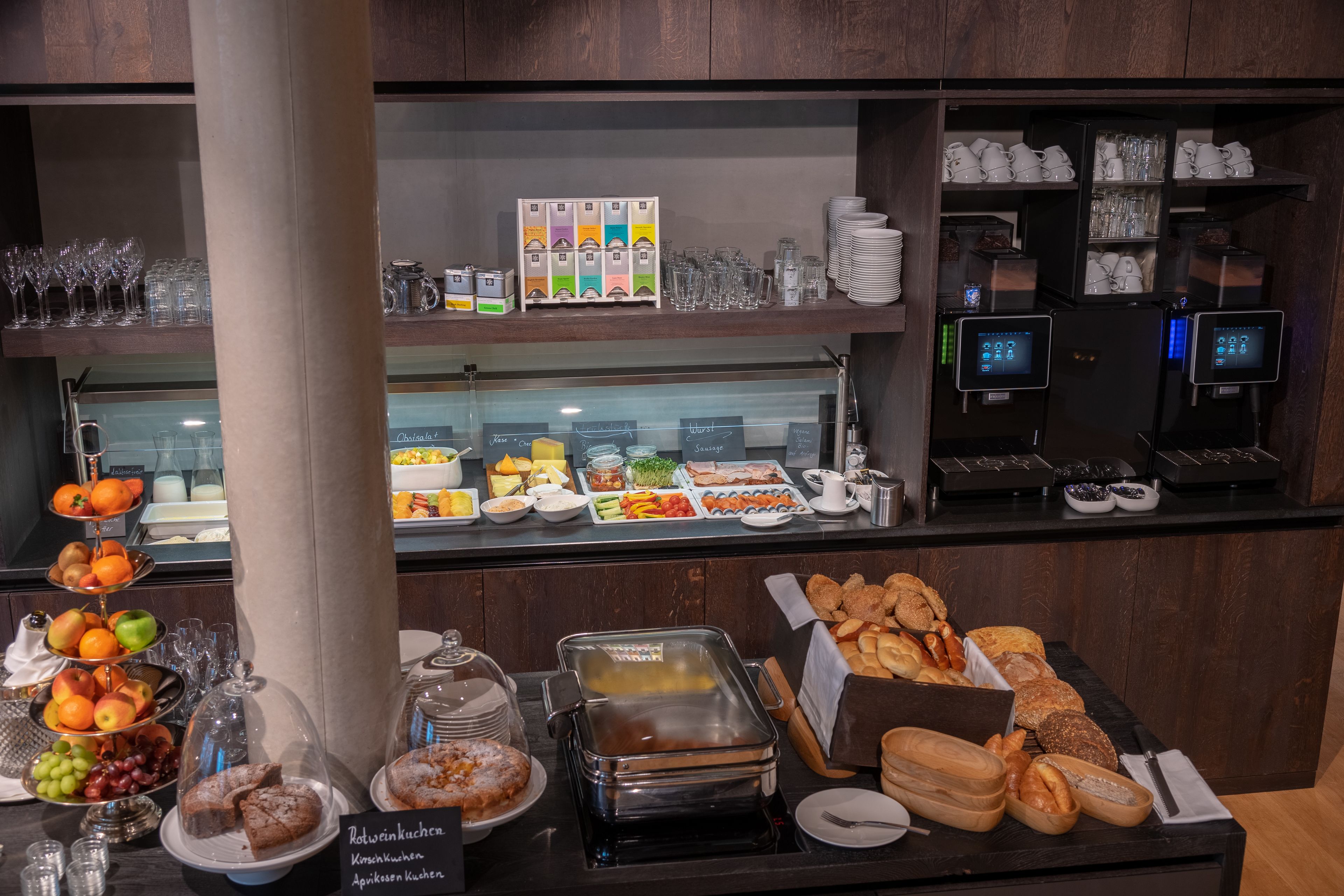 A buffet area with various food options, including fruits, pastries, and beverages.