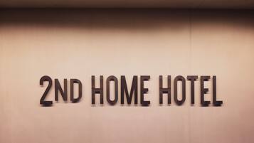 Paredes com o texto "2ND HOME HOTEL", indicando o nome do estabelecimento.