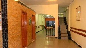 A hallway with a wooden door, a staircase, and a view of a dining area. - Amazon Dream Hostel (Iquitos)