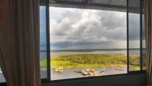 A room with a large window overlooking a lake and forested area. - Amazon Dream Hostel (Iquitos)