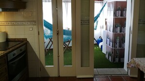 A kitchen with a double door leading to a patio area with a hammock and a small garden. - Casa da Travessa (Ponte de Lima)