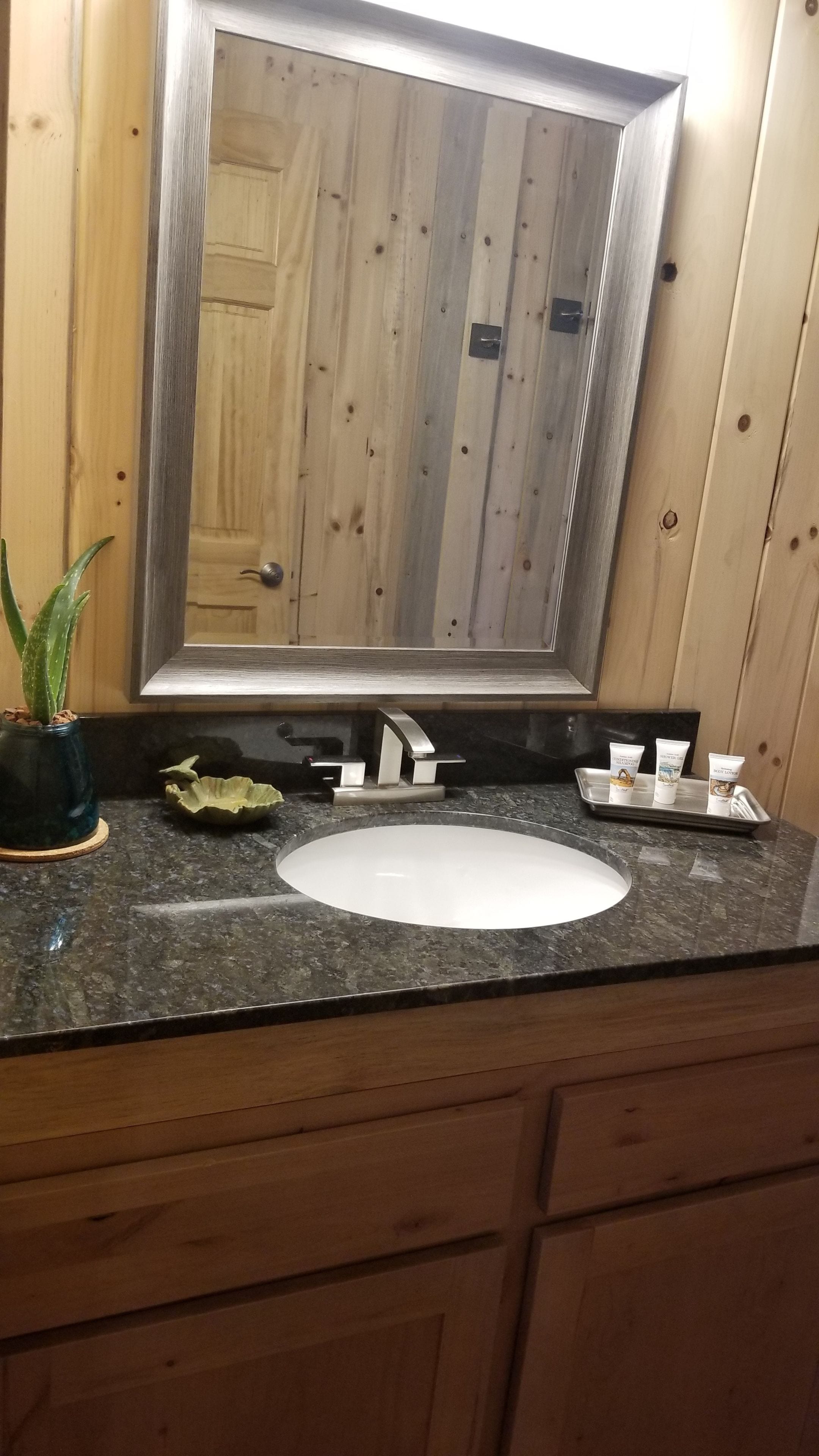 Une salle de bain avec un meuble-lavabo en bois, un évier, un miroir et des articles de toilette.