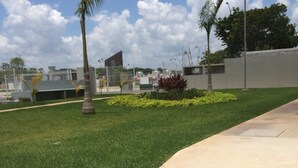 A paved pathway with a grassy area and palm trees. - Olivos Apart (Playa del Carmen)
