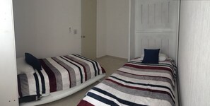 Un alojamiento pequeño de una sola habitación con dos camas, cada una con ropa de cama a rayas.