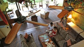A spacious living area with a large ceiling fan, a sofa set, and a coffee table with decorative items. - Hawaiian Sanctuary (Pahoa)