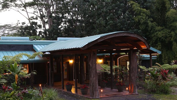 A covered outdoor area with a curved roof, surrounded by lush greenery and potted plants. - Hawaiian Sanctuary (Pahoa)