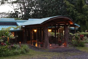 A covered outdoor area with a curved roof, surrounded by lush greenery and potted plants. - Hawaiian Sanctuary (Pahoa)