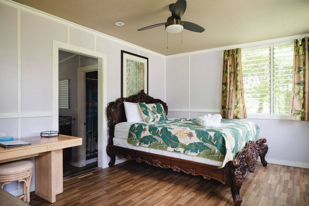 A bedroom with a wooden bed, a desk, and a ceiling fan.