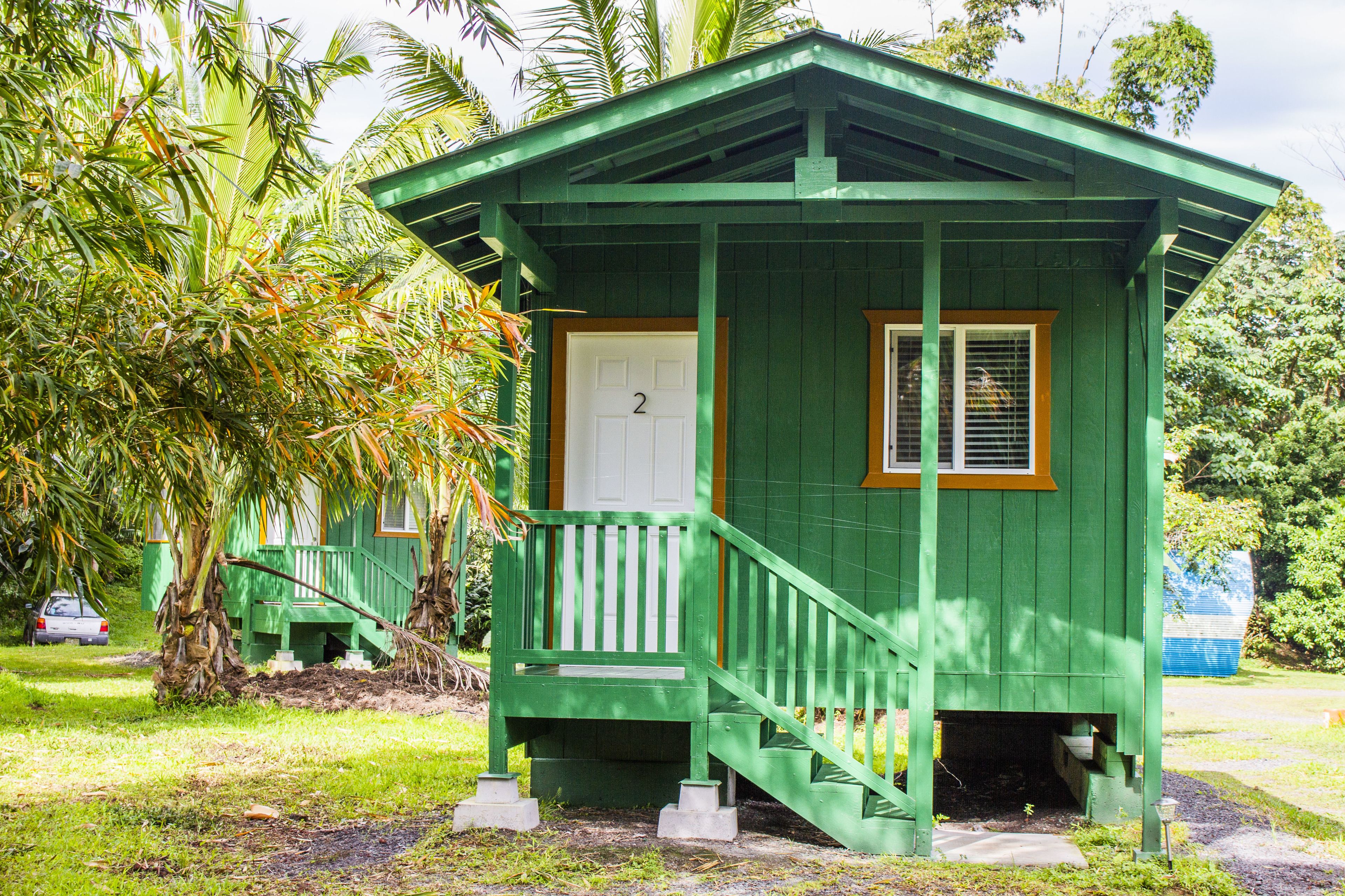A small, single-story, green wooden building with a white door and a number "2" on it.