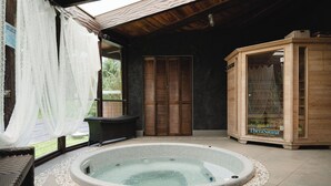 A spa area with a hot tub, wicker furniture, and a wooden sauna. - Hawaiian Sanctuary (Pahoa)