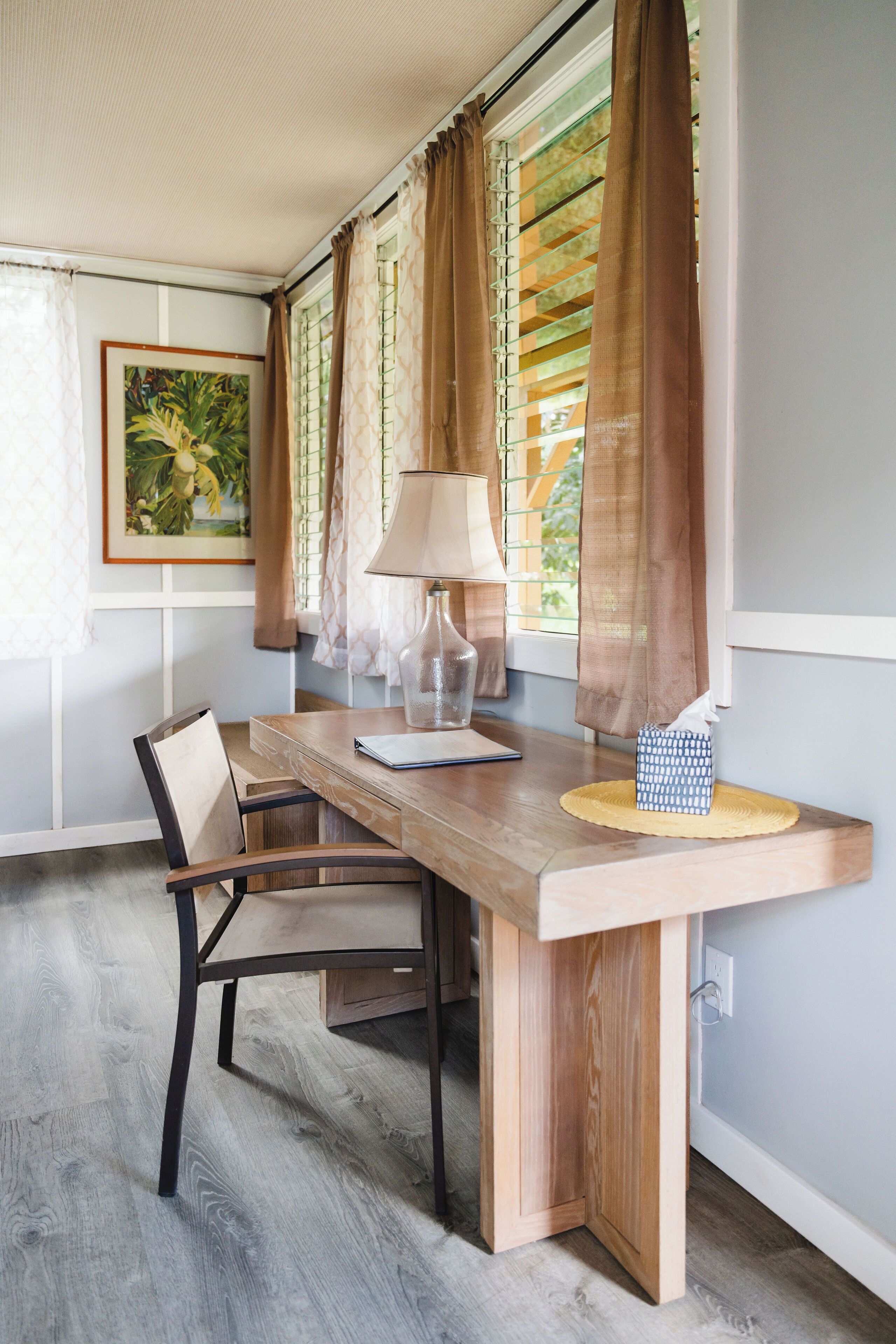 Un'area pranzo con un tavolo di legno, sedie, una lampada e un quadro appeso al muro.
