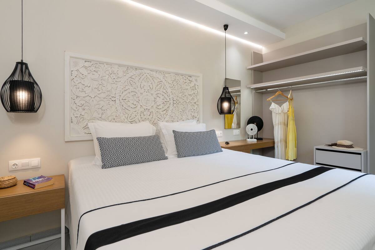 Un dormitorio moderno con una cama grande, dos mesitas de noche, un armario y paneles decorativos en la pared.