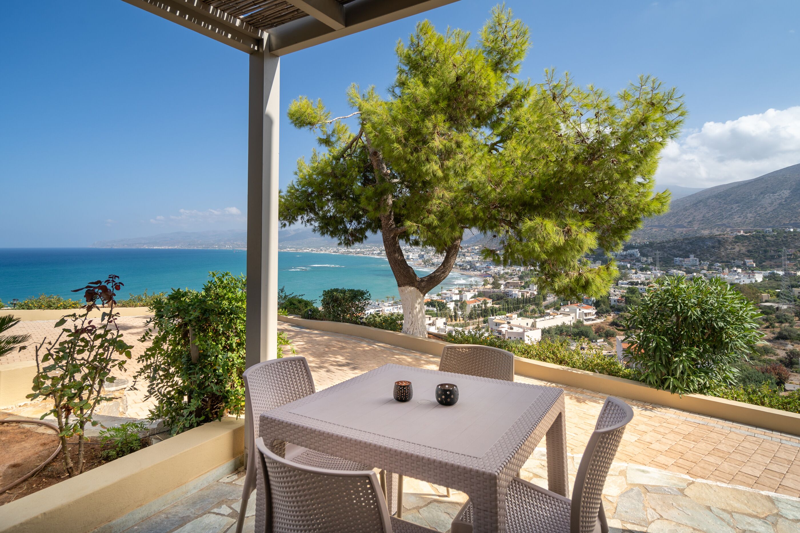 Um terraço com móveis de vime, uma mesa e duas velas.