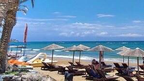 A beach with lounge chairs, umbrellas, and a boat.