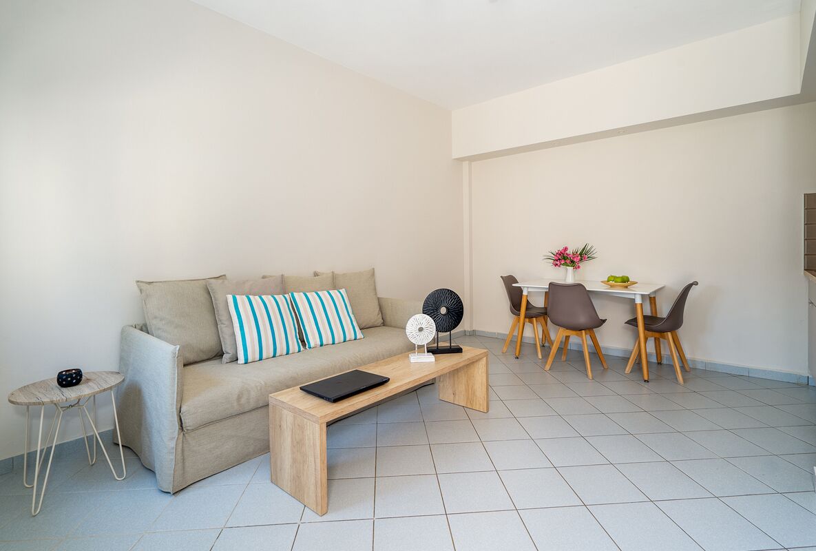 Un salon moderne comprenant un canapé, une table basse, une petite table d’appoint et un coin repas avec une table et des chaises.