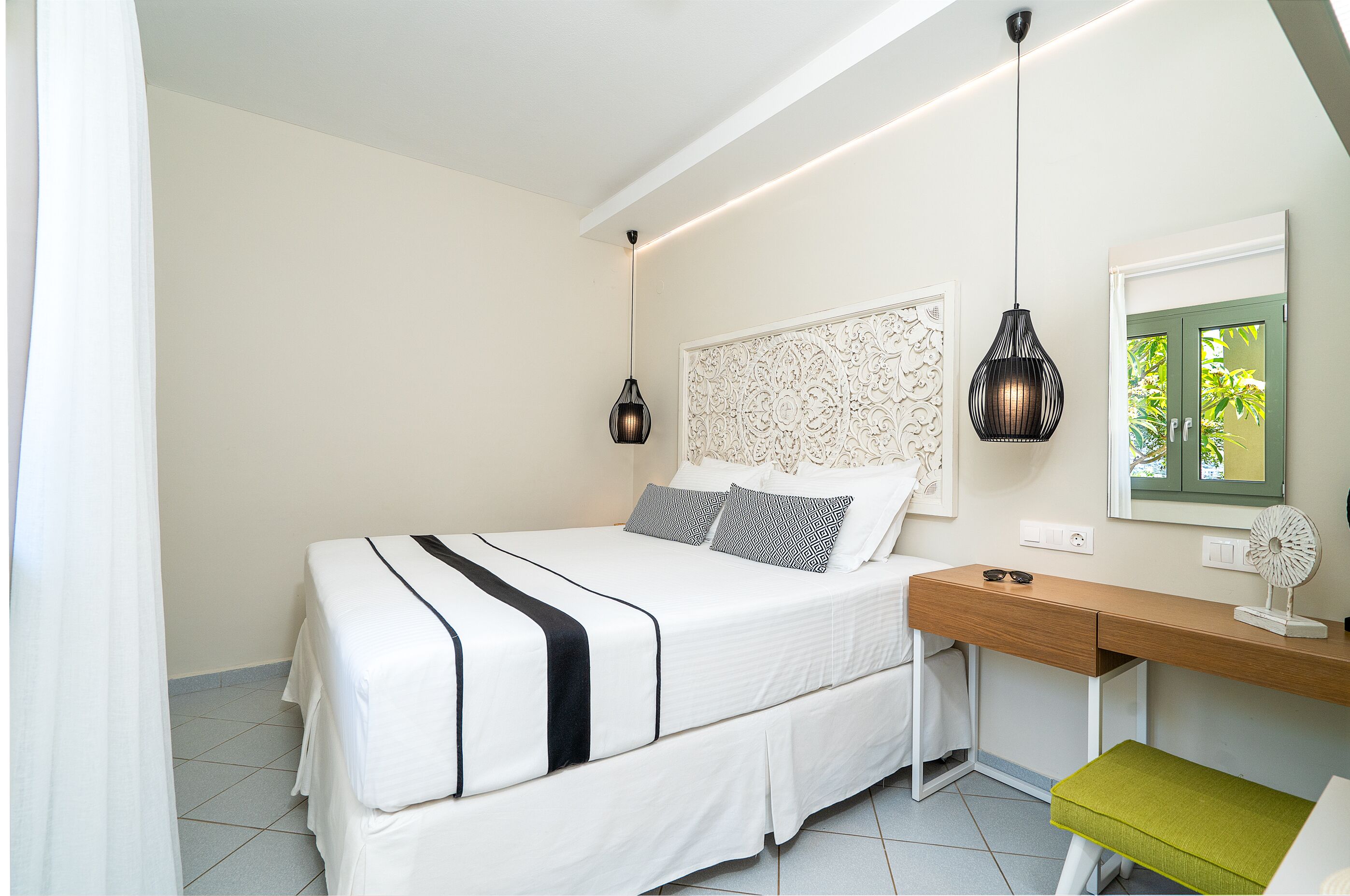 A neatly arranged bedroom with a bed, bedside table, and a desk with a chair.